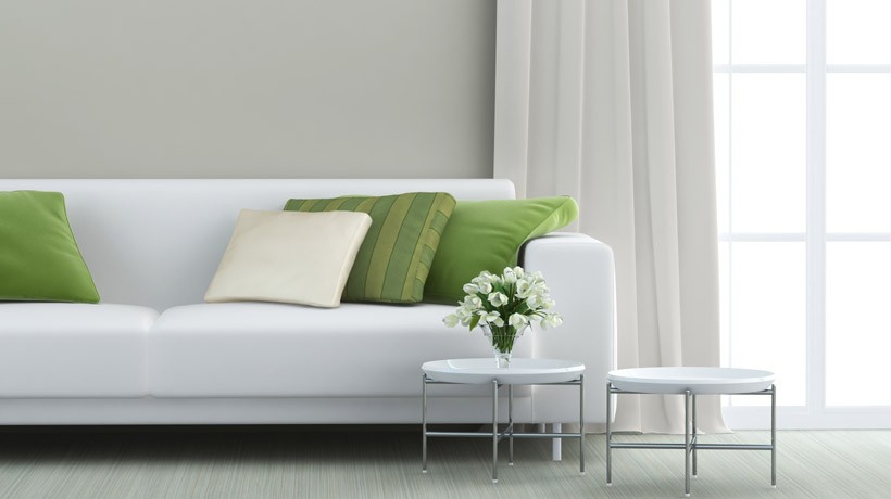 Sofá branco com almofadas verdes em uma sala iluminada