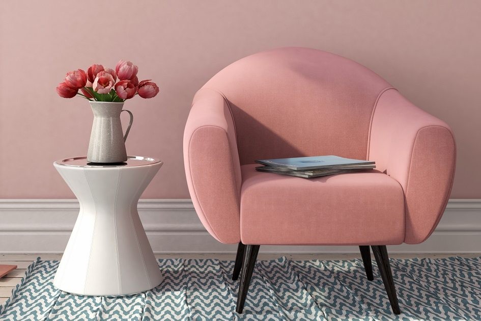 Poltrona rosa ao lado de uma mesa com flores