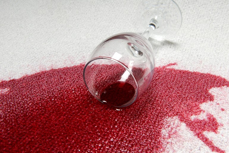 Taça com líquido vermelho derramado sobre um tapete claro
